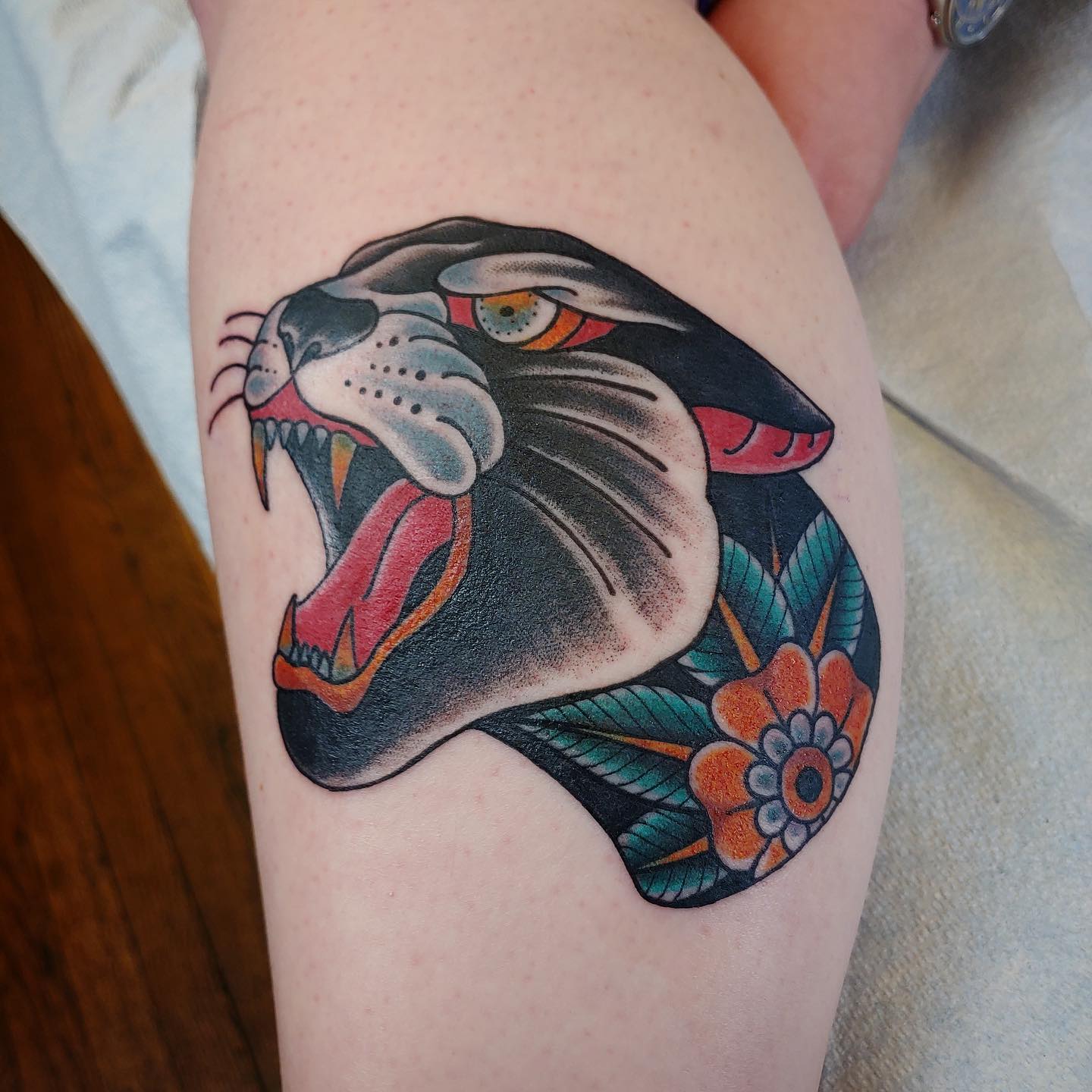 Lower leg tattoo of a colorful wild cat showing its teeth