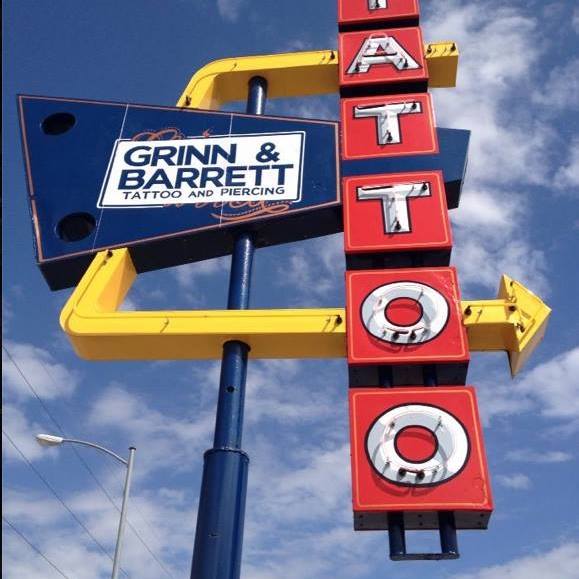 Retro blue, yellow and red neon business sign that says "Grinn & Barrett Tattoo Studio"